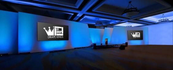 Angled Modular Backdrop with two front projection screens and blue up lighting on white walls for corporate meeting