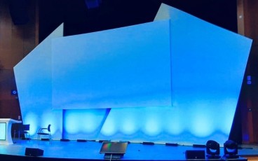 Angled single screen AV-Drop Modular Backdrop up lit in blue for corporate event